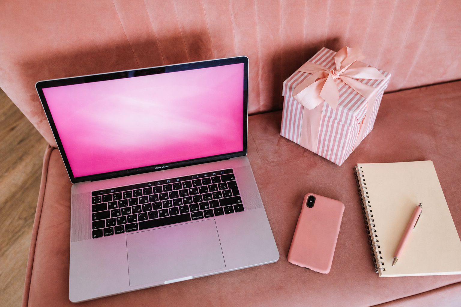 &Auml;sthetischer Arbeitsplatz mit Laptop Handy Notizbuch und kleinem Geschenk